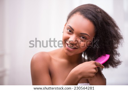 Beautiful  dark skinned girl combing her hair with rose comb  isolated on white background smiling looking at camera with copy place