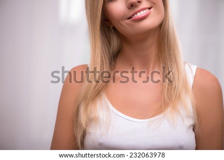 Beautiful happy  blond girl with straight  hair in white  T shirt  with plump rose lips and white teeth smiling looking at camera    close up