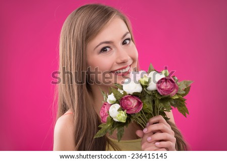 Portrait of happy beautiful brown haired girl holding  bunch of roses on rose background smiling looking at camera