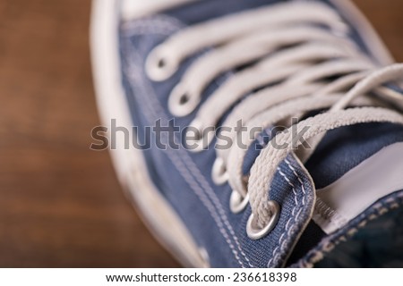 cool blue  gym shoes with white laces  on brown parquet  wooden floor  close up