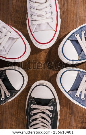 cool youth white blue black  gym shoes standing in circle  on brown parquet  wooden floor top view