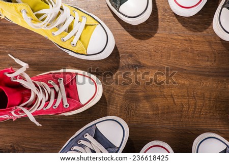 cool youth white yellow red blue black  gym shoes standing in circle  on brown parquet  wooden floor with copy place  top view