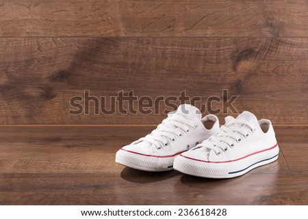 cool youth white gym shoes with red and blue stripes  on brown parquet  wooden floor with copy place