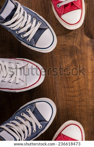 cool youth white red blue black  gym shoes standing in semicircle on brown parquet  wooden floor with copy place