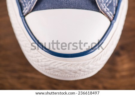 cool blue  gym shoes with white laces  on brown parquet  wooden floor  close up