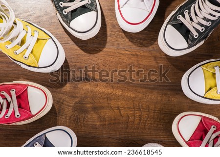 cool youth white yellow red blue black  gym shoes standing in circle  on brown parquet  wooden floor with copy place  top view
