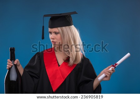 Portrait of beautiful disappointed  blond girl in black cloak and master hat thinking her wish holding bundle of sheet of paper and bottle on blue background smiling looking at it