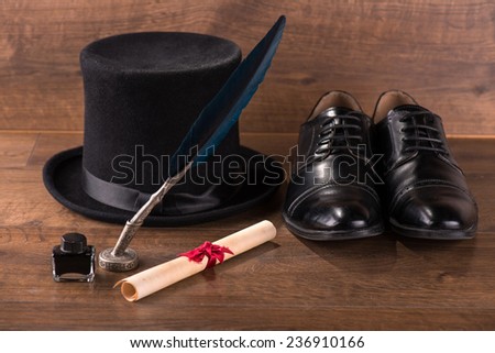 black classic  hat near refined  black patent leather shoes  and bundle and ink and black feather on brown parquet  wooden floor