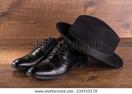 black classic  hat on refined  black patent leather shoes  on brown parquet  wooden floor