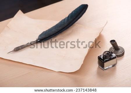 ink and beautiful artificial black feather  on old yellow paper