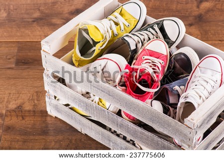 several  pairs of cool youth red blue white yellow  gym shoes in box   on brown wooden floor