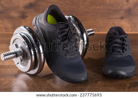 black  gym shoes near sport weight   on brown parquet  wooden floor