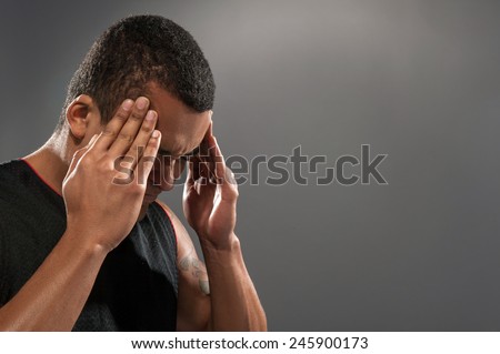 Feeling headache after workout. Side view mage of young muscular African man holding head in hands and keeping eyes closed while standing against grey background