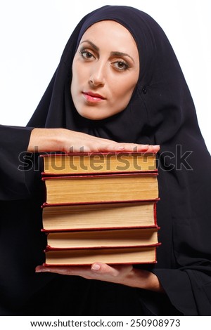 Where traditions meet the future. Image of beautiful young Muslim woman in chador holding a heap of books and smiling isolated on grey background