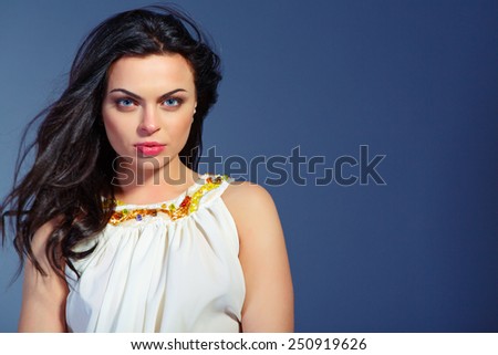 Pure femininity. Conceptual photo of elegant beautiful woman with long Ã?Â?Ã?Â�urly hair looking at camera with passionate face expression while sitting against dark background with copy space