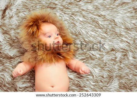 Fluffy cuttie. Top view of an adorable baby wearing a fur hat and lying on the fur blanket