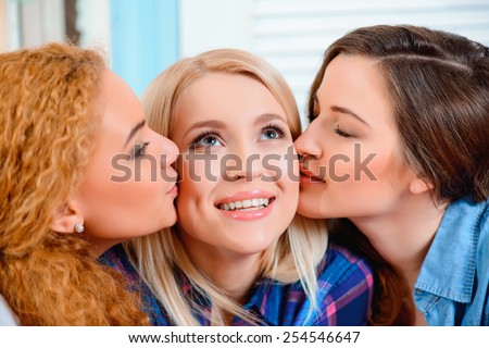 Best friends for life. Three young beautiful female friends sitting in cafe and kissing each other