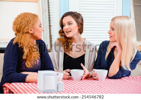 Catching up with old friends. Three young  beautiful female friends sitting in cafe and talking