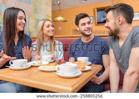 Enjoying coffee with great people. Four friends laughing and drinking coffee while having breakfast in the cafe