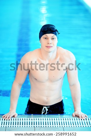 Born to swim. Young handsome man with naked torso wearing a swimming cap and goggles while standing in the swimming pool
