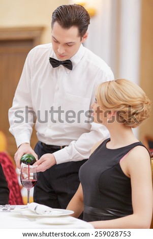 It is our best wine. Handsome waiter serving wine to his beautiful female client while sitting in the luxury restaurant