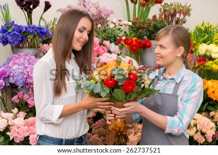 This bouquet is marvelous. Smiling florist and attractive female customer holding a beautiful floral arrangement