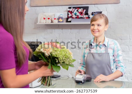 Perfect choice.  Selective focus of a florist using a point of sale terminal for purchase of a bouquet which holds a client