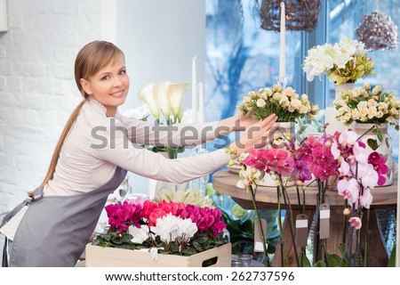 Each bouquet is gorgeous. Attractive smiling florist arranging pots at her flower shop