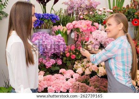 Only the freshest flowers. Young smiling florist showing flowers to the customer at the flower store