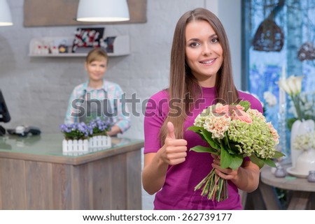 Best flowers for special occasion. Attractive young woman holding a bouquet raises her thumb up showing satisfaction with the purchase