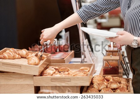 Croissants taste good with jam. Close up of female hand taking croissant to her plate