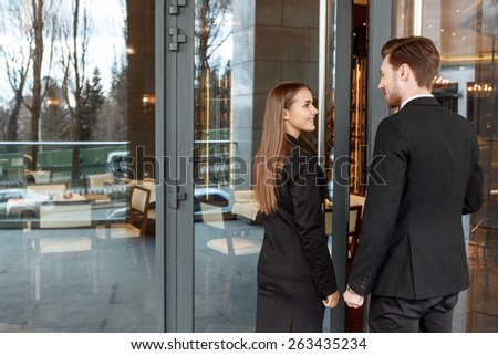 Long-awaited meeting. Businessman and businesswoman smiling to each other open the door of the luxury restaurant