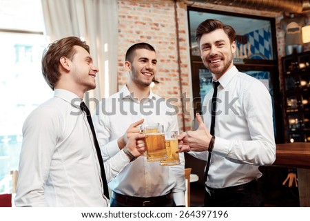 Best company for the Friday night party. Four friends businessmen drink beer and rejoice together at the bar