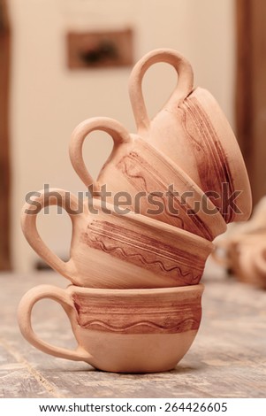 Beautiful clay cups. Life still of the perfectly made clay cups with tiny ornament set in figures on the pottery wooden table