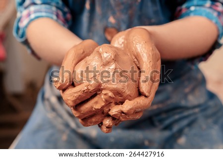 Clay ball. Close-up of female hands holding a ball made of clay to start working on the wheel