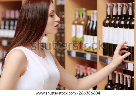 Sweet memories. Cropped shot of a young attractive woman touching with tips of her fingers label of the wine bottle in a liquor store
