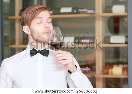 Professional sommelier. Close-up of a young sommelier testing wine flavor with his eyes closed