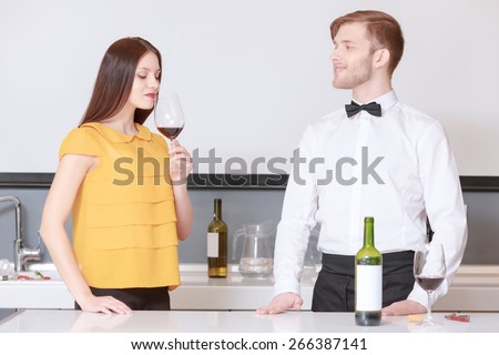 Fabulous aroma of wine. Young beautiful woman smelling glass of wine during wine degustation while sommelier looks at her satisfied with the effect