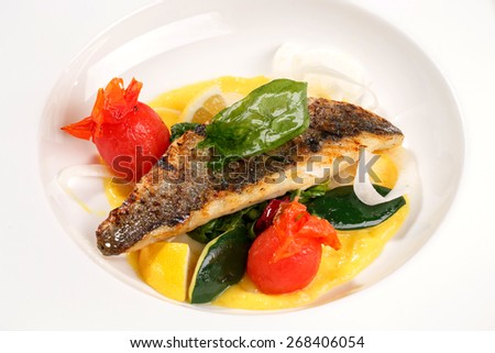 Fried fish with zucchini, tomatoes grill, slices of lemon and sauce