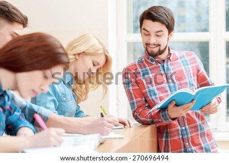 Preparing for the exam. Young bearded student checking the answers of his female peer at college