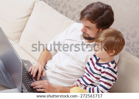 Digital age. Top view of a young handsome man and his son using computer in a living room