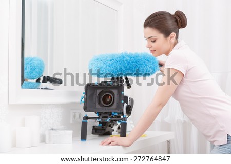 Professional cleaning. Young woman standing with blue cleaning sweep and making video camera ready to shoot
