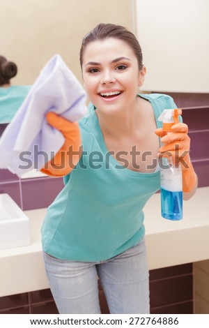 Hey it is cleaning time. Hilarious Young woman acting like cleaning with mean of wash and in orange rubber gloves