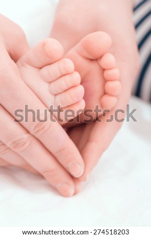 Gentle touch. Woman holding tiny baby feet in her hands like a heart