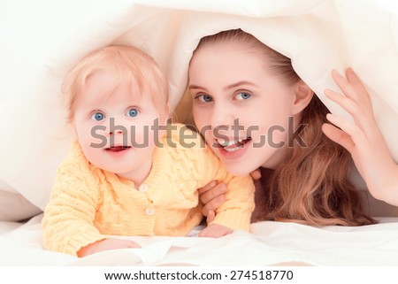 Happy motherhood. Happy mother hiding with her smiling baby under the blanket