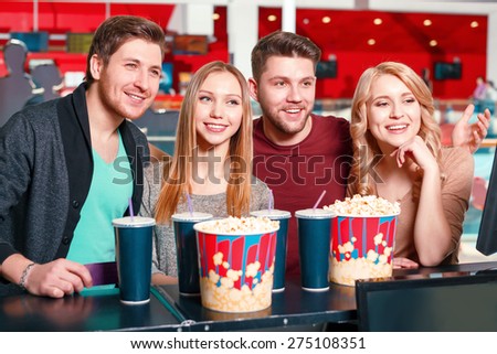 Full size popcorn. Group of young smiling people buying popcorn and coke before watching film in cinema