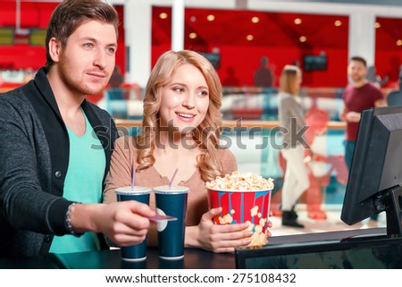 To add enjoyment. Couple of young people buying popcorn and coke before watching film in cinema.