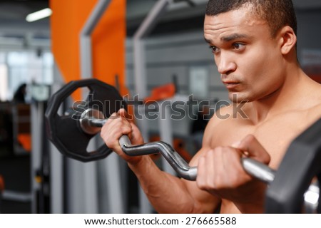 Paying hard. Portrait of  muscular weightlifter with barbell in his hands in sport gym.