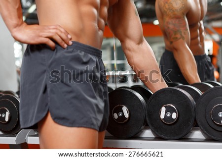 You need it. Close up of muscular man choosing barbell in gym sport club.