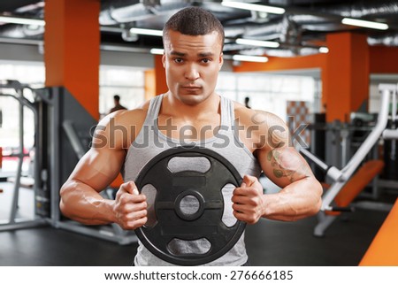 Getting to point. Portrait of muscular powerlifter with weight disk in his hands on sport gym club.